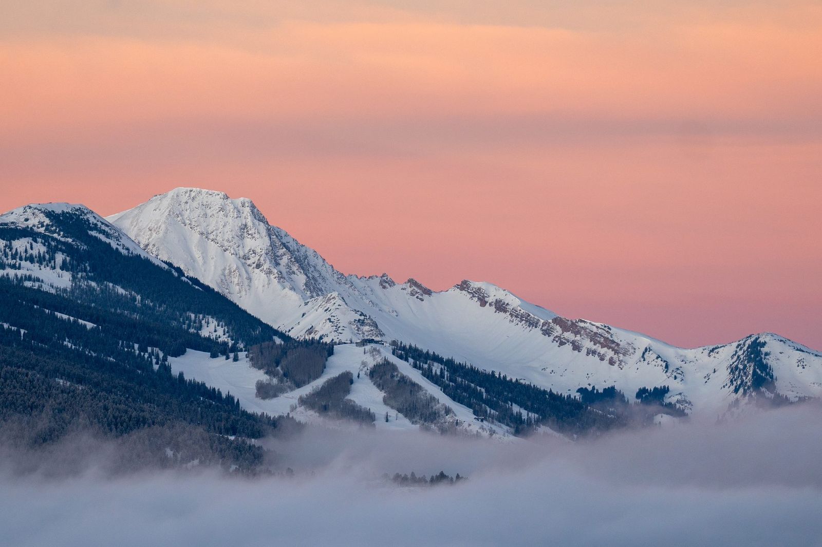 Cordillera nevada de Colorado emergiendo sobre un mar de nubes al atardecer